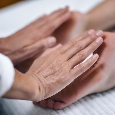 Image: Reiki practitioner applying healing to patient's feed.